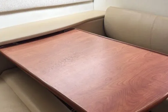 Slide: The Image of Interior dining area of a 2004 Bayliner 285 Cruiser with a wooden table and beige seating. - 9