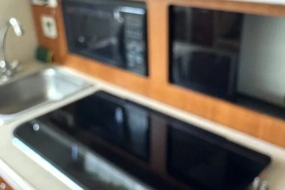 Slide: The Image of 2004 Bayliner 285 Cruiser kitchen area with sink, stove, and microwave. - 10