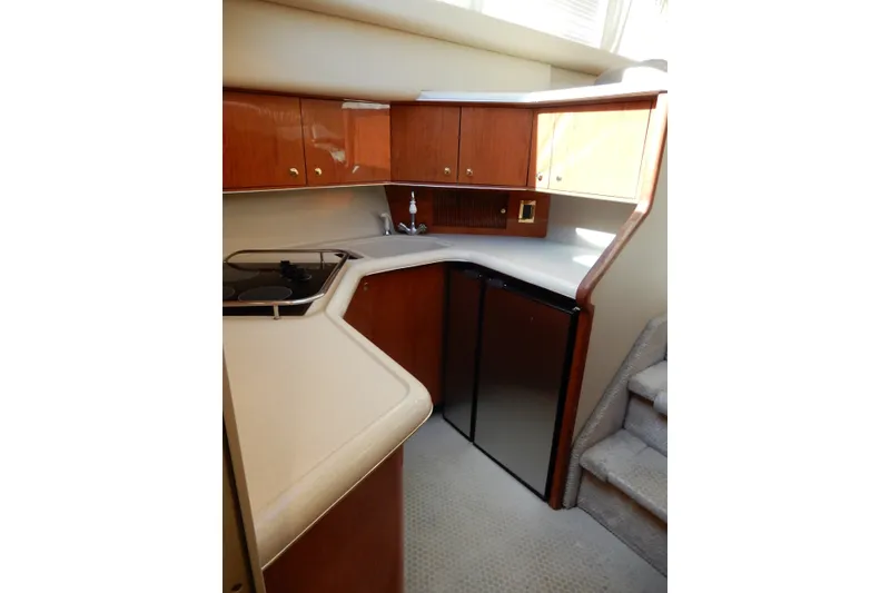 Slide: The Image of 2000 Sea Ray 380 Aft Cabin yacht kitchen with wood cabinets and compact appliances. - 48