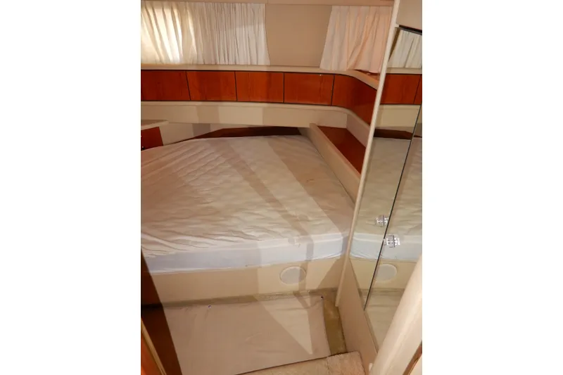 Slide: The Image of 2000 Sea Ray 380 Aft Cabin bedroom with bed, wooden accents, and curtains. - 68