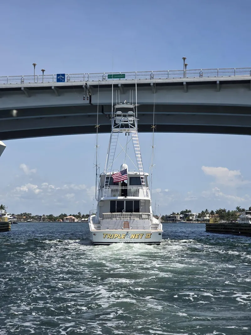 Slide: The Image of Hatteras 82 Convertible yacht from 1994 passing under a bridge on a sunny day. - 39