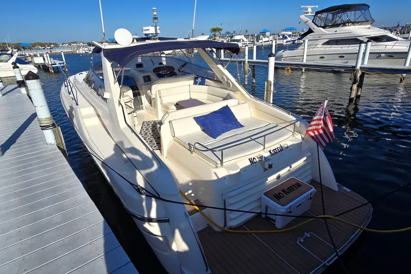 Slide: The Image of 1994 Sunseeker Mustique 42 yacht docked at marina, featuring spacious seating and American flag. - 4