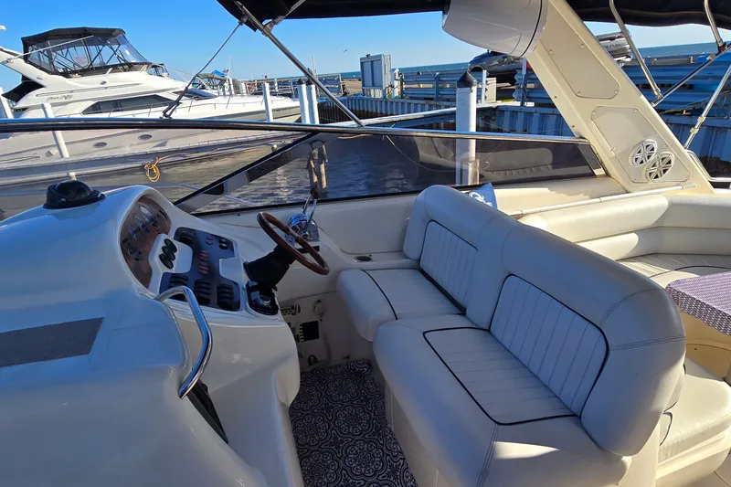Slide: The Image of Interior view of a 1994 Sunseeker Mustique 42 yacht with white seating and helm. - 10