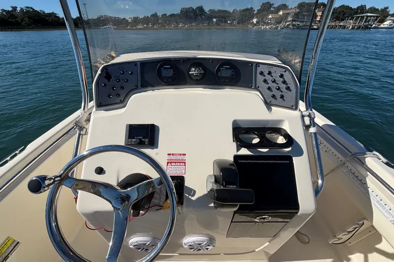 Slide: The Image of 2016 Scout 210 XSF boat dashboard with steering wheel and controls on water. - 12