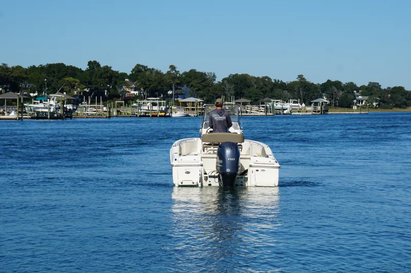Slide: The Image of 2016 Scout 210 XSF boat cruising on a calm blue lake near a marina. - 4
