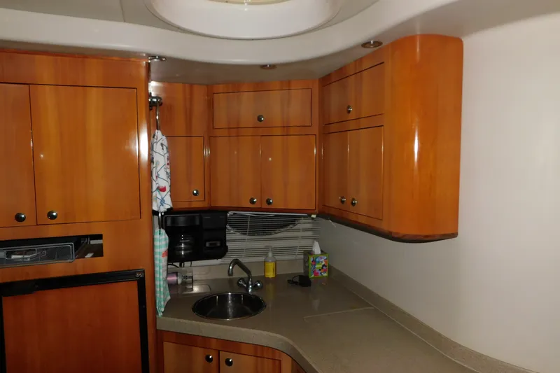 Slide: The Image of 2004 Regal Commodore 3860 yacht kitchen with wooden cabinets and compact sink area. - 77