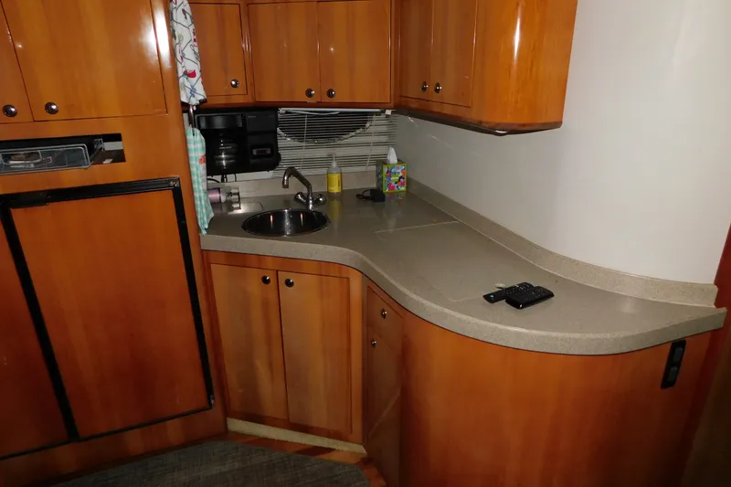 Slide: The Image of 2004 Regal Commodore 3860 yacht kitchen with wooden cabinets and compact sink area. - 76