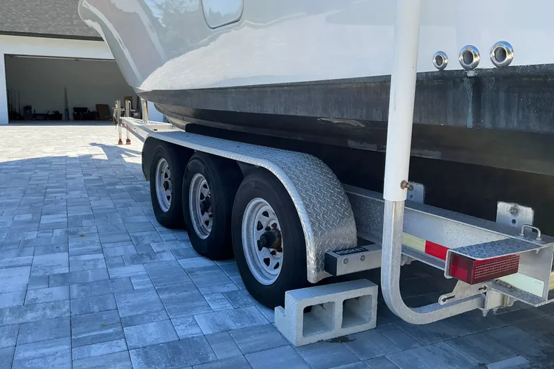 Slide: The Image of 2019 Sportsman Open 312 Center Console on a triple-axle trailer in a paved driveway. - 60