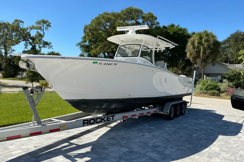 Slide: The Image of 2019 Sportsman Open 312 Center Console boat on trailer in sunny driveway. - 17