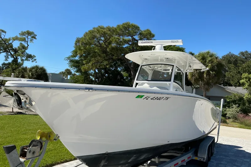 Slide: The Image of 2019 Sportsman Open 312 Center Console boat on trailer, sunny day, lush greenery. - 18