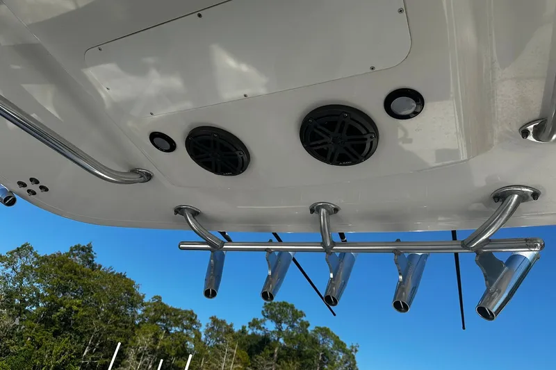 Slide: The Image of 2016 Regulator 28 Forward Seating boat with rod holders and speakers, under clear blue sky. - 29