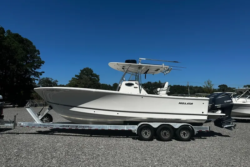 Slide: The Image of 2016 Regulator 28 Forward Seating boat on trailer, parked outdoors under clear blue sky. - 0