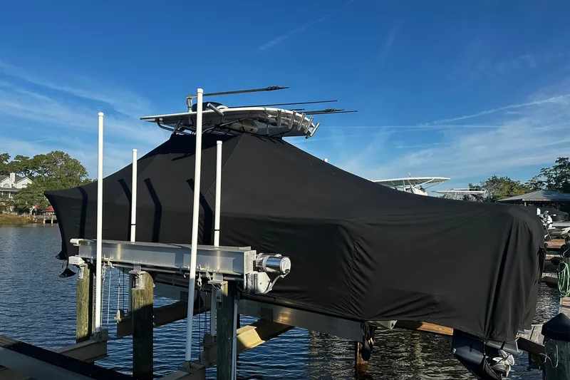 Slide: The Image of Covered 2016 Regulator 28 Forward Seating boat on lift by the water. - 7