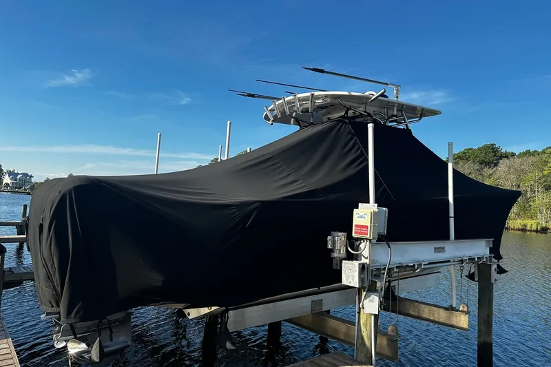 Slide: The Image of 2016 Regulator 28 Forward Seating boat covered on a lift by the water. - 6