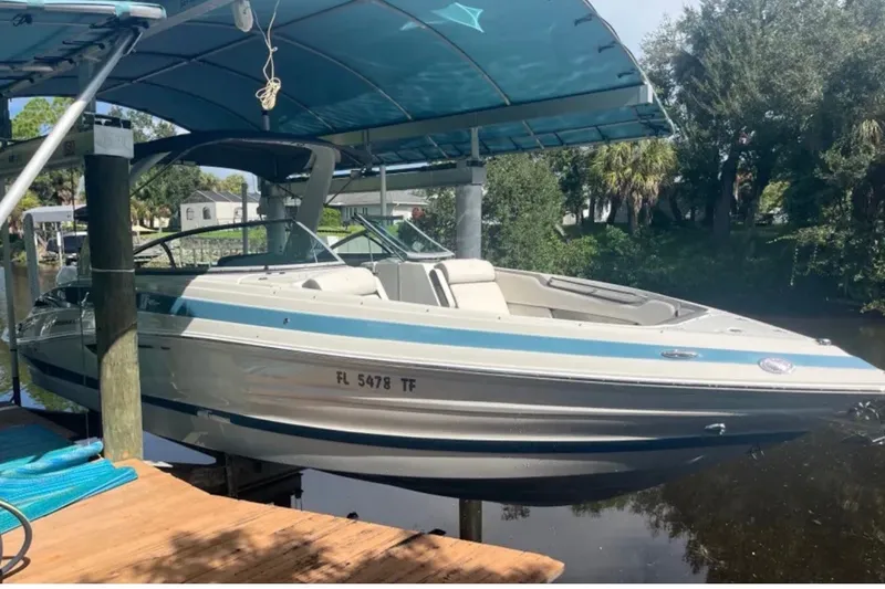 The Image of 2022 Crownline 290 XSS boat docked under a canopy on a sunny day. - 2