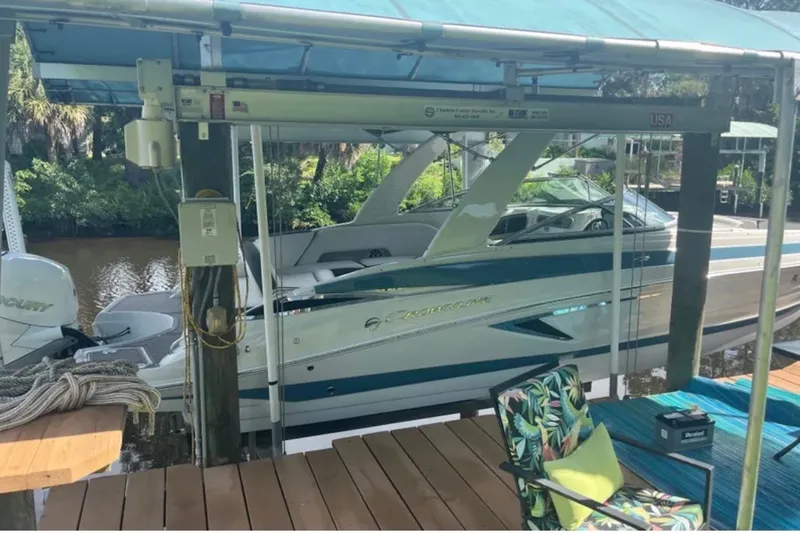 Slide: The Image of 2022 Crownline 290 XSS boat docked under a canopy, surrounded by lush greenery. - 1