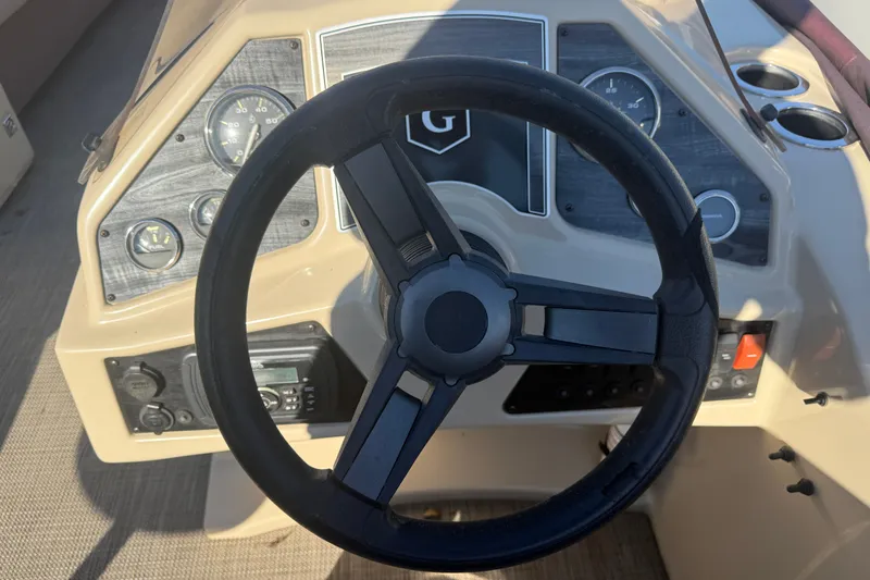 Slide: The Image of Steering wheel and dashboard of a 2018 Sweetwater 22 boat, featuring gauges and controls. - 11