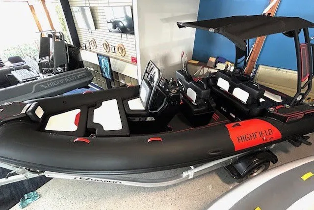 Slide: The Image of 2026 Highfield Velox 560 boat with black and red design in showroom. - 2