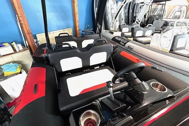 Slide: The Image of 2026 Highfield Velox 560 boat interior with black and red seating, steering wheel, and cup holders. - 7