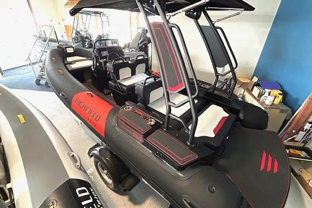 Slide: The Image of 2026 Highfield Velox 560 inflatable boat with sleek black and red design in showroom. - 4
