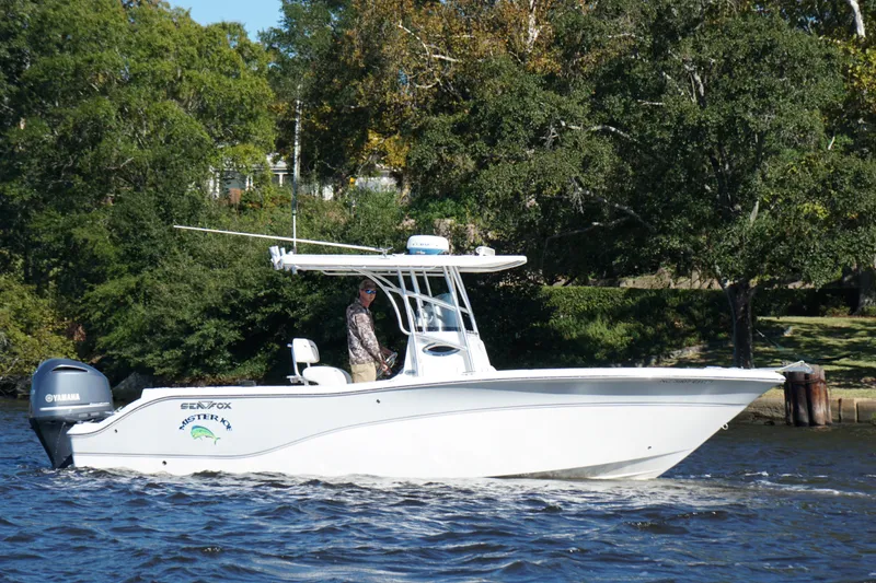 Slide: The Image of 2012 Sea Fox 256 Center Console boat cruising on a river with lush green trees. - 2