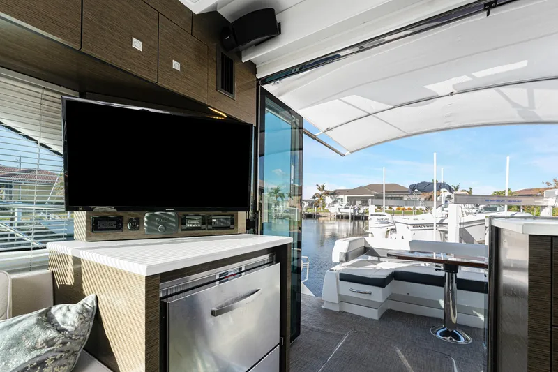 Slide: The Image of 2018 Cruisers Yachts 50 Cantius interior with TV, seating, and marina view. - 43