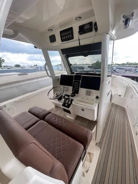 Slide: The Image of 2014 Everglades 325 Center Console boat interior with brown seating and modern controls. - 25