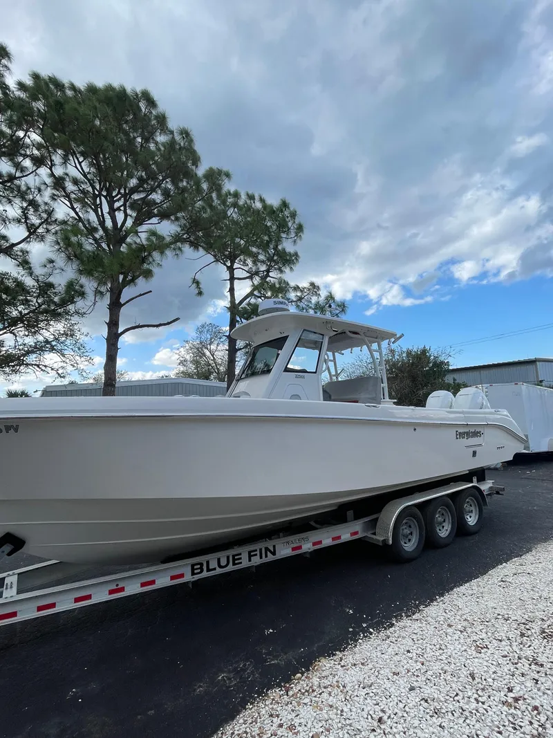 The Image of 2014 Everglades 325 Center Console boat on trailer, parked outdoors under cloudy sky. - 0