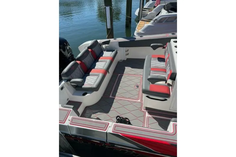 Slide: The Image of 2022 Fountain 38 SC boat interior with gray and red seating, docked by the water. - 8