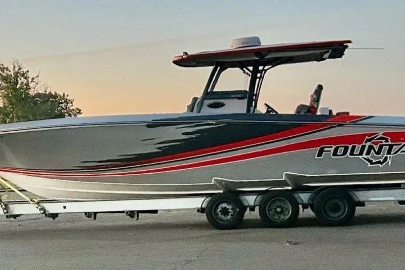 Slide: The Image of 2022 Fountain 38 SC boat on trailer at sunset, sleek design with red accents. - 10