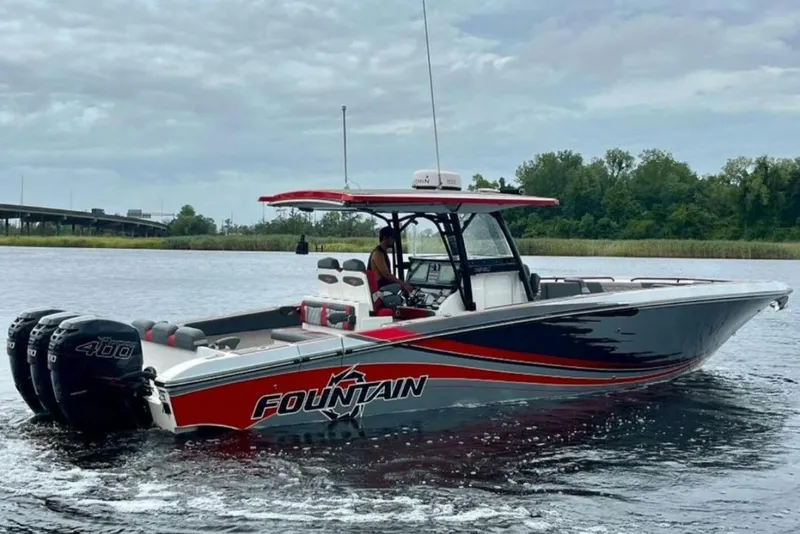 The Image of 2022 Fountain 38 SC boat cruising on a calm river with triple 400 engines. - 1
