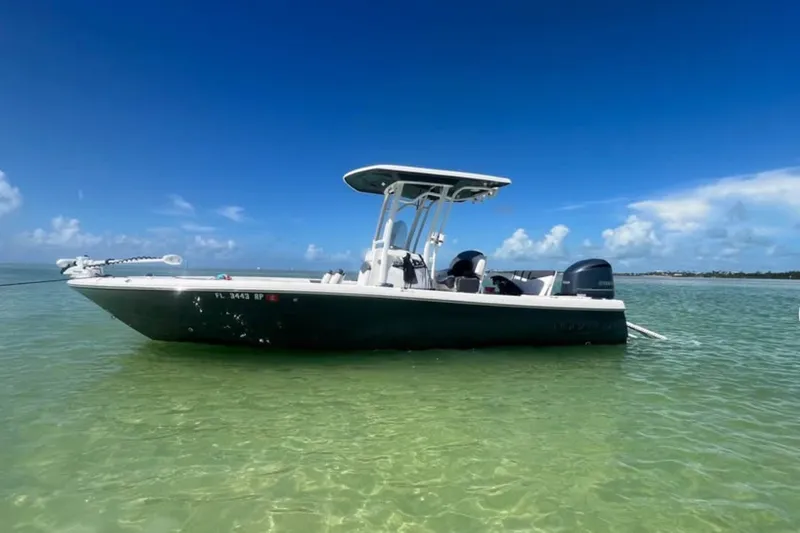The Image of 2018 Robalo 246 Cayman boat anchored in clear, shallow water under a bright blue sky. - 1