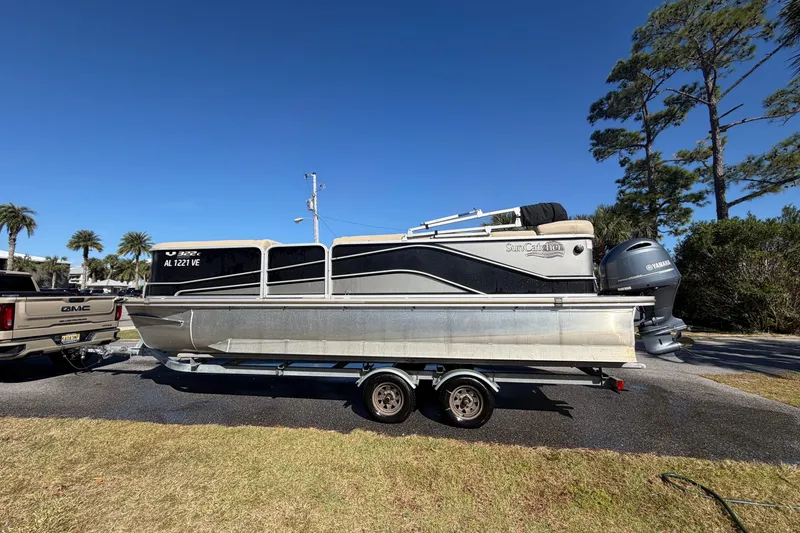 Slide: The Image of 2020 SunCatcher V322C pontoon boat on trailer, parked outdoors under clear blue sky. - 1