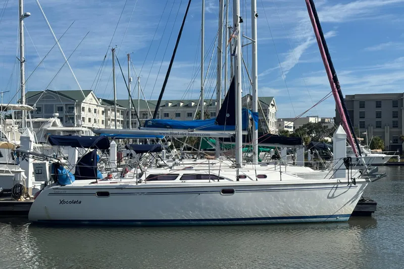 The Image of 2006 Catalina 320 sailboat docked in marina, clear sky, residential buildings in background. - 1