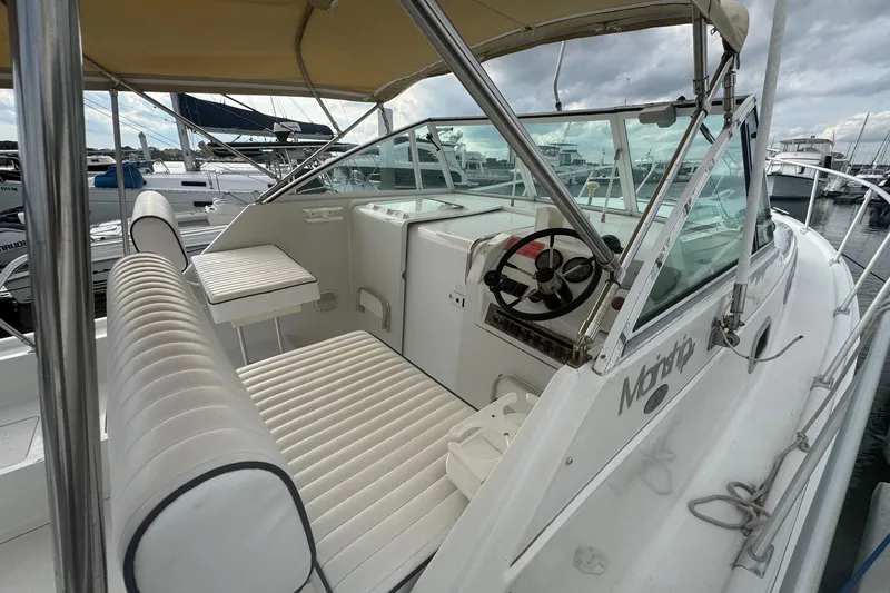 Slide: The Image of 2000 Mainship Pilot 30 boat interior with helm, seating, and canopy at marina. - 10