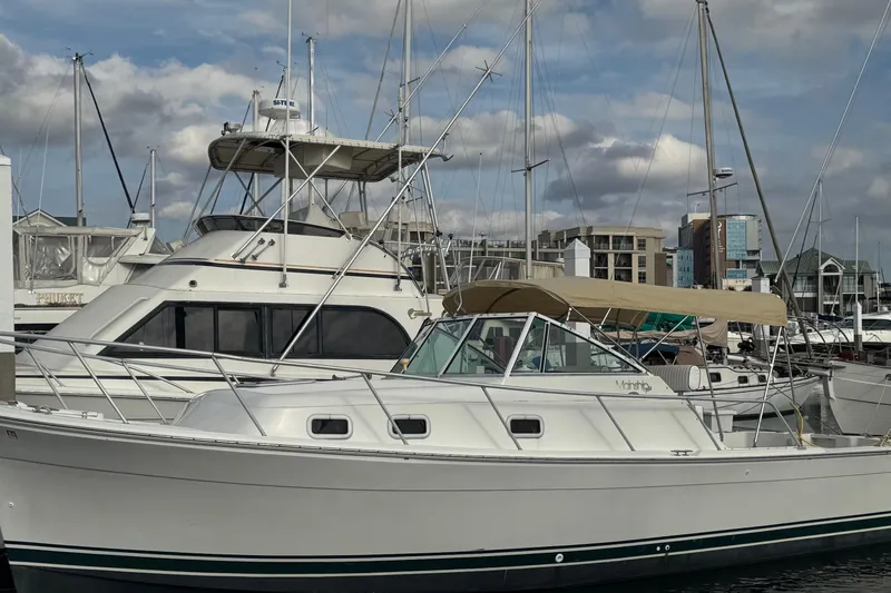 Slide: The Image of 2000 Mainship Pilot 30 boat docked at marina with other vessels in background. - 6