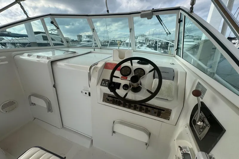 Slide: The Image of 2000 Mainship Pilot 30 boat helm with steering wheel and control panel, docked at marina. - 17