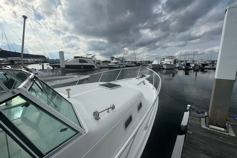 Slide: The Image of 2000 Mainship Pilot 30 docked at marina under cloudy sky. - 11