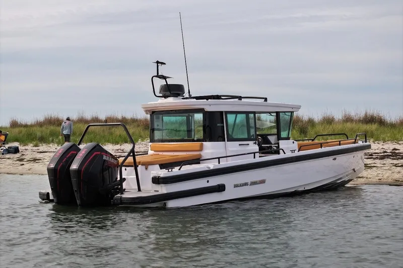 Slide: The Image of 2021 Axopar Brabus 28 Cabin boat docked on a sandy shore. - 17