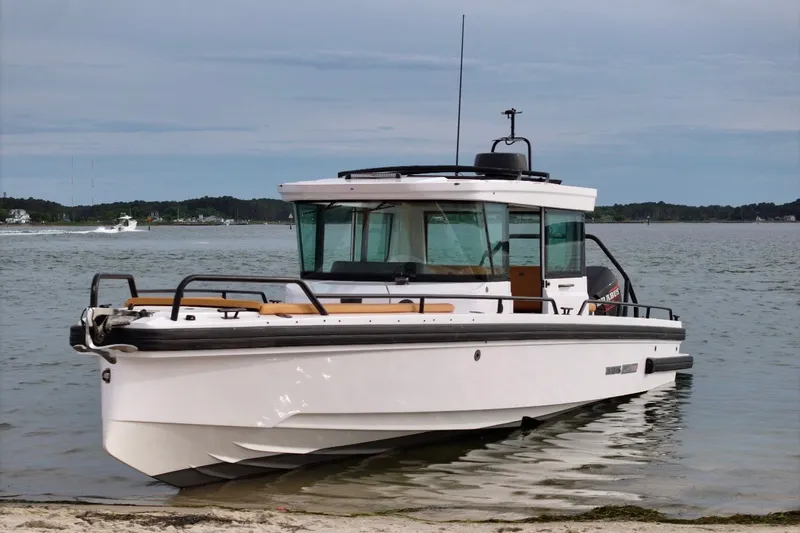 Slide: The Image of 2021 Axopar Brabus 28 Cabin boat docked on a calm shoreline. - 12