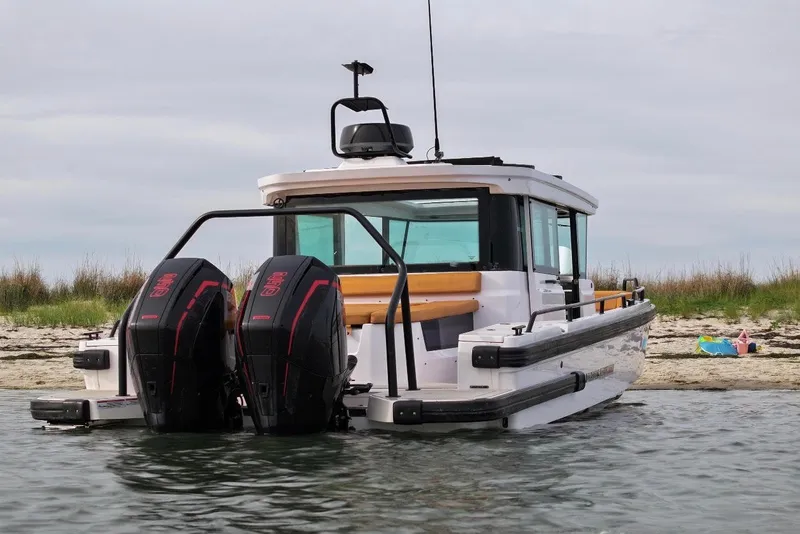 Slide: The Image of 2021 Axopar Brabus 28 Cabin boat with dual engines near a sandy shore. - 13