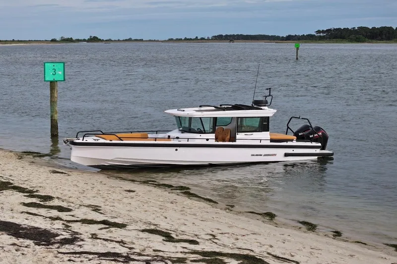 Slide: The Image of 2021 Axopar Brabus 28 Cabin boat docked on a sandy shore. - 3