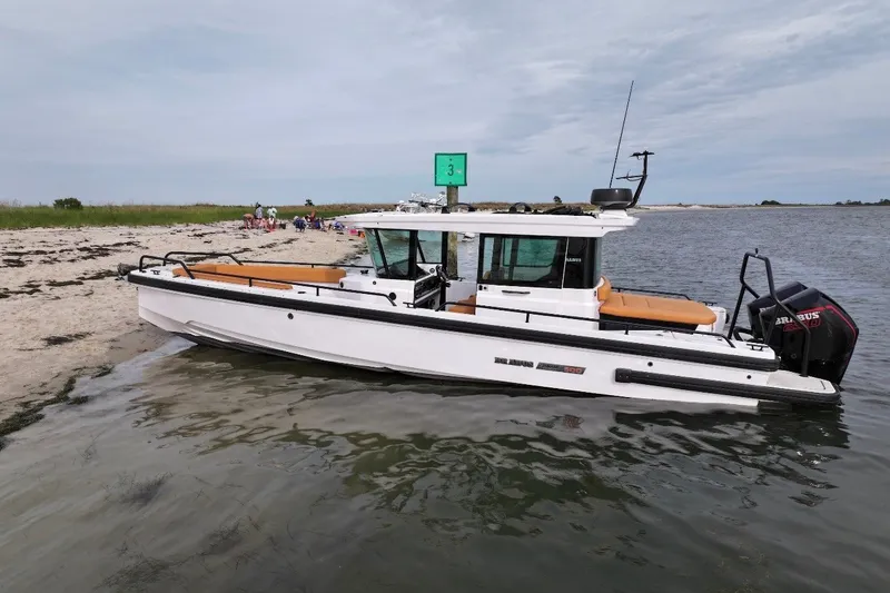 Slide: The Image of 2021 Axopar Brabus 28 Cabin boat docked on a sandy beach. - 5