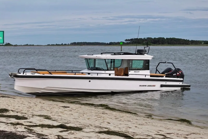 Slide: The Image of 2021 Axopar Brabus 28 Cabin boat docked on a sandy shore. - 1