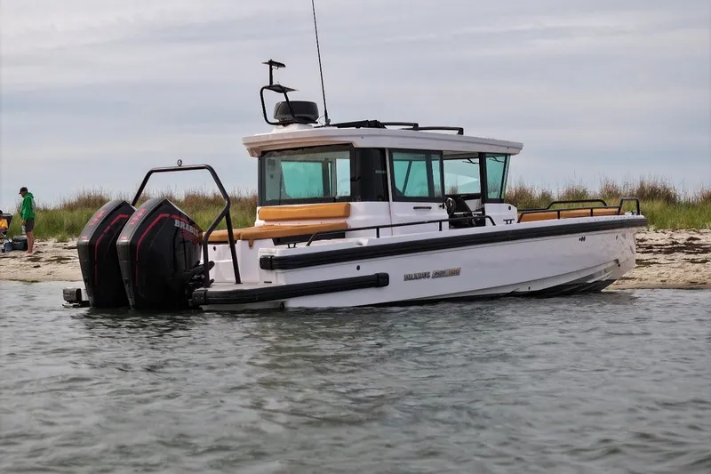 Slide: The Image of 2021 Axopar Brabus 28 Cabin boat docked on a sandy shore. - 7