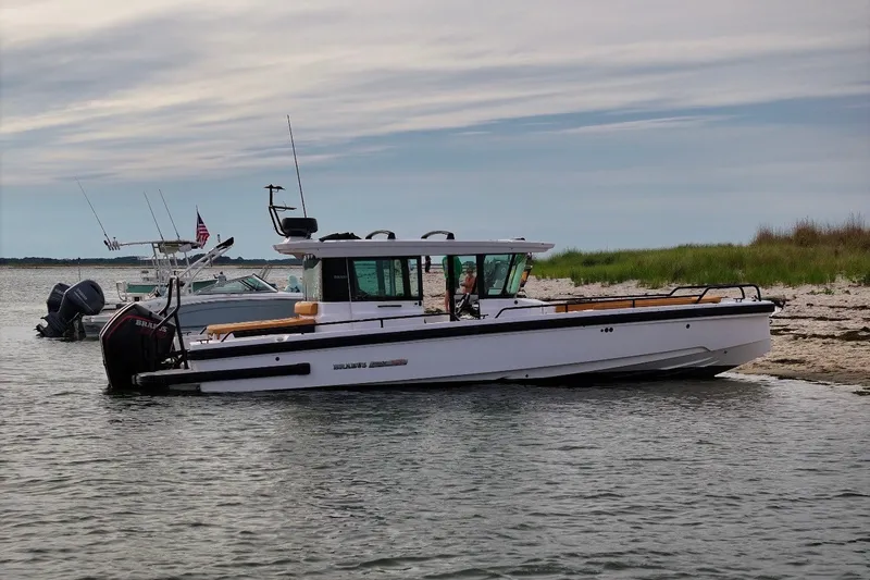 Slide: The Image of 2021 Axopar Brabus 28 Cabin boat docked on a sandy shore. - 8