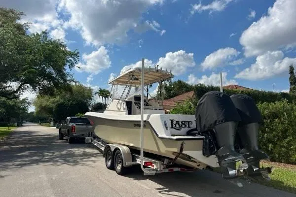 Slide: The Image of 2004 Contender 31 Fisharound boat on trailer, parked on a sunny residential street. - 2