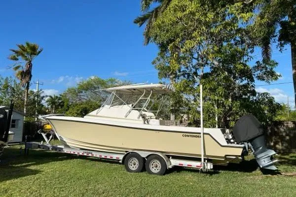 Slide: The Image of 2004 Contender 31 Fisharound boat on trailer, parked on grass under clear blue sky. - 3