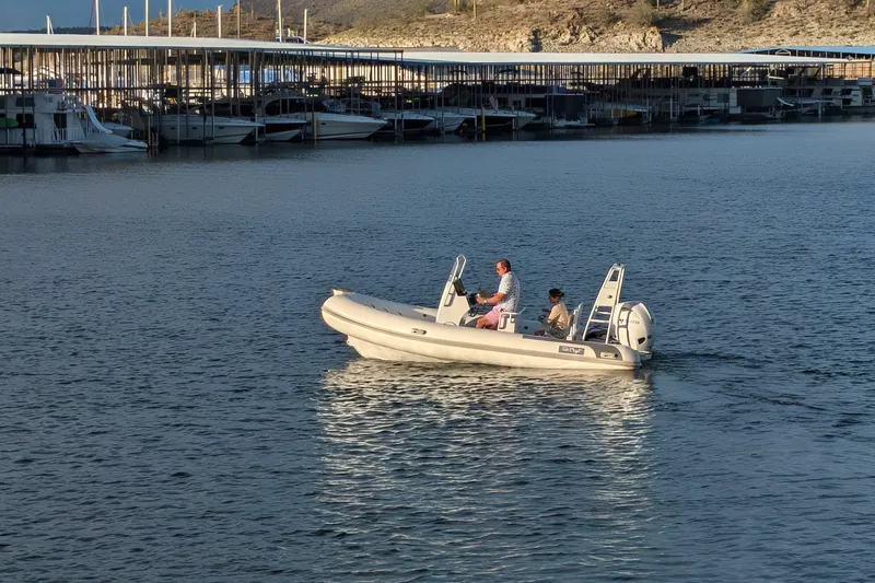 Slide: The Image of 2027 Tide Craft Sanibel 17 Demo Boat cruising on a calm lake near a marina. - 13
