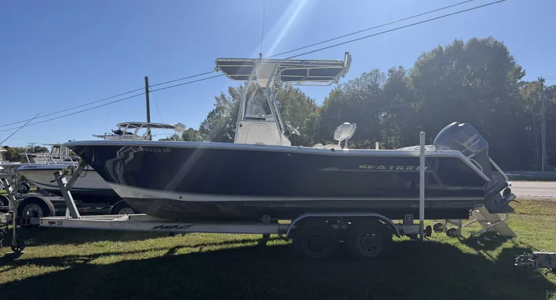 Slide: The Image of A 2013 Sea Hunt Ultra 225 on a trailer, featuring a T-top and outboard motor. - 1